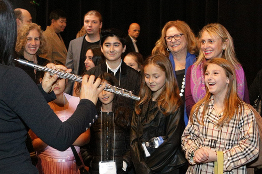 Kids smiling and watching flautist perform backstage