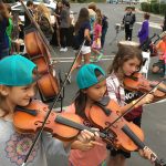 Three small girls trying out violins