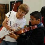 Teacher showing boy how to hold violin