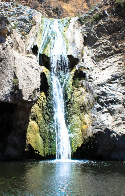 Waterfall over moss covered rock wall