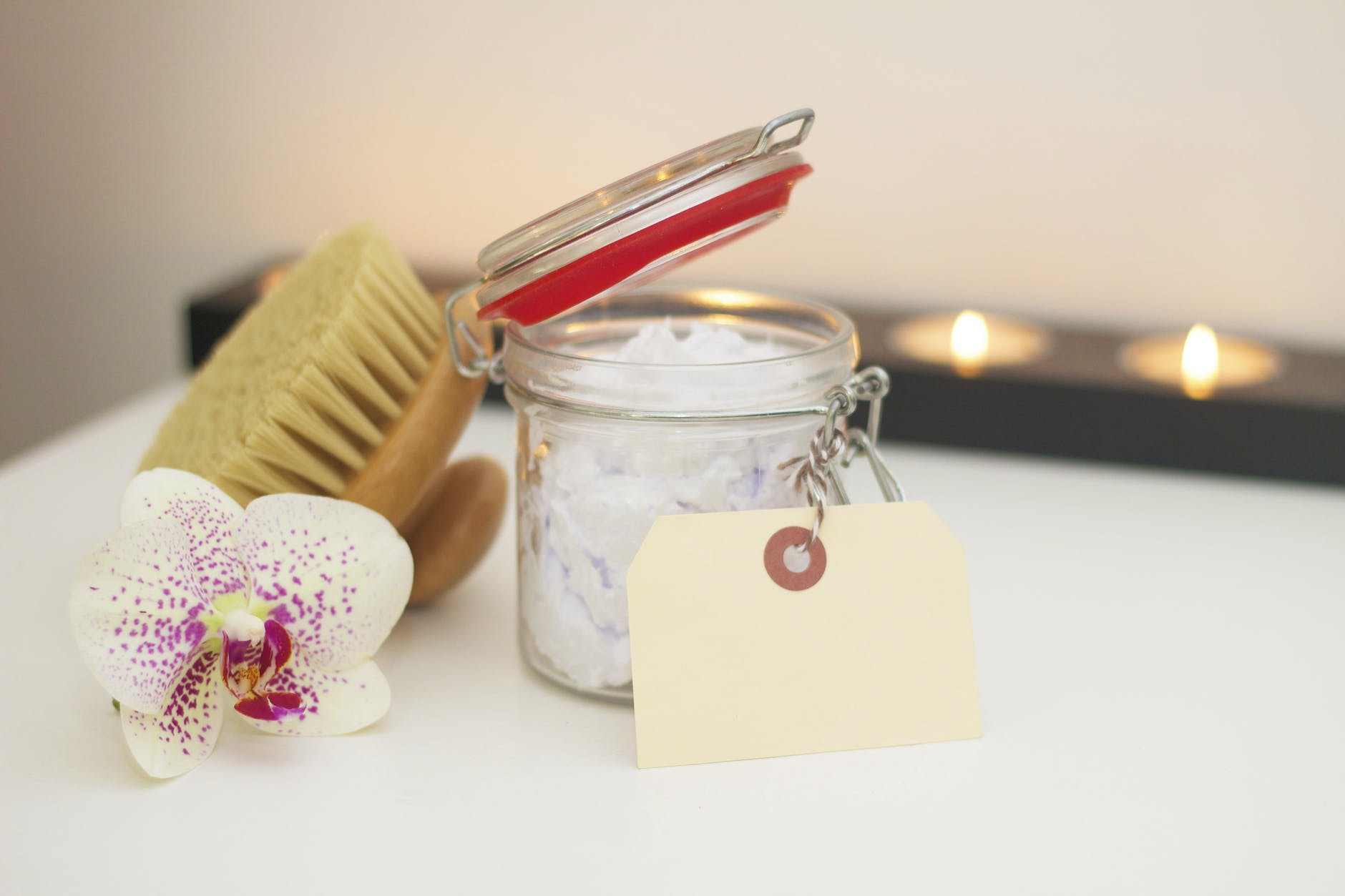 Skincare cream and brush, votive candles behind